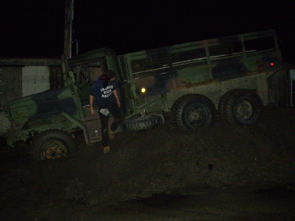 Person next to a muddy military truck at night