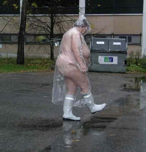 1989 Ford Bronco - A person wearing a clear plastic bag as a makeshift poncho walks through puddles on a wet asphalt surface. The person is wearing white boot…