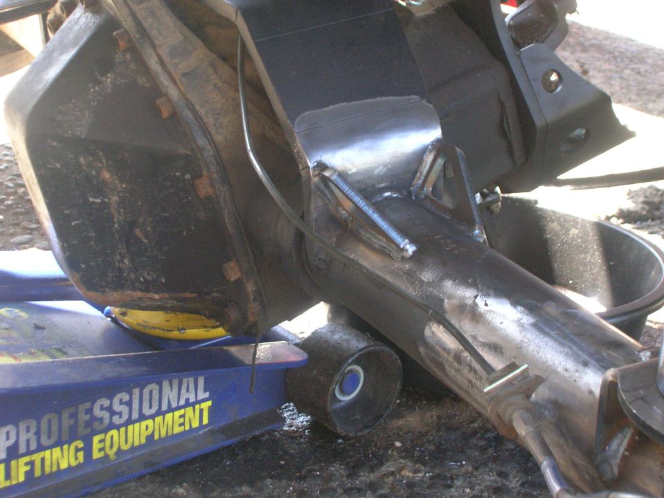 Vehicle rear axle assembly on a blue hydraulic floor jack, showing modifications.