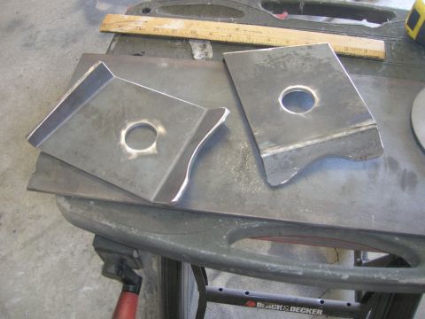 1996 Ford Bronco - Two custom metal fabricated parts with circular cutouts are shown on a workbench. A wooden ruler is visible in the background.