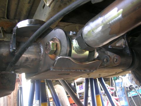 1996 Ford Bronco - Close-up view of the suspension linkage and mounting hardware on a vehicle, likely a Ford Bronco, supported by blue jack stands.