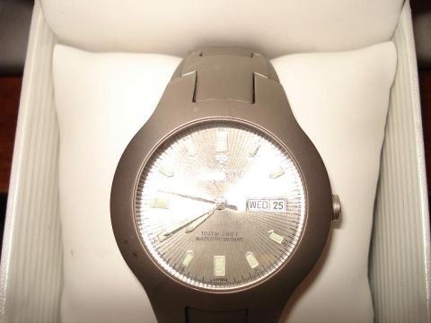 2000 Ford Crown Victoria - A close-up shot of a watch face with a silver dial and a date window showing "WED 25". The watch is resting on a white cushion inside a box.