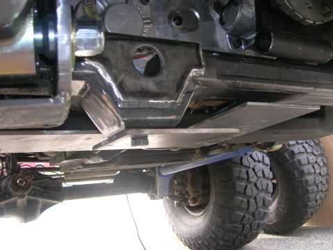 1996 Ford Bronco - The underside of a vehicle shows a custom metal skid plate assembly bolted to the frame, protecting the drivetrain components. Large off-ro…