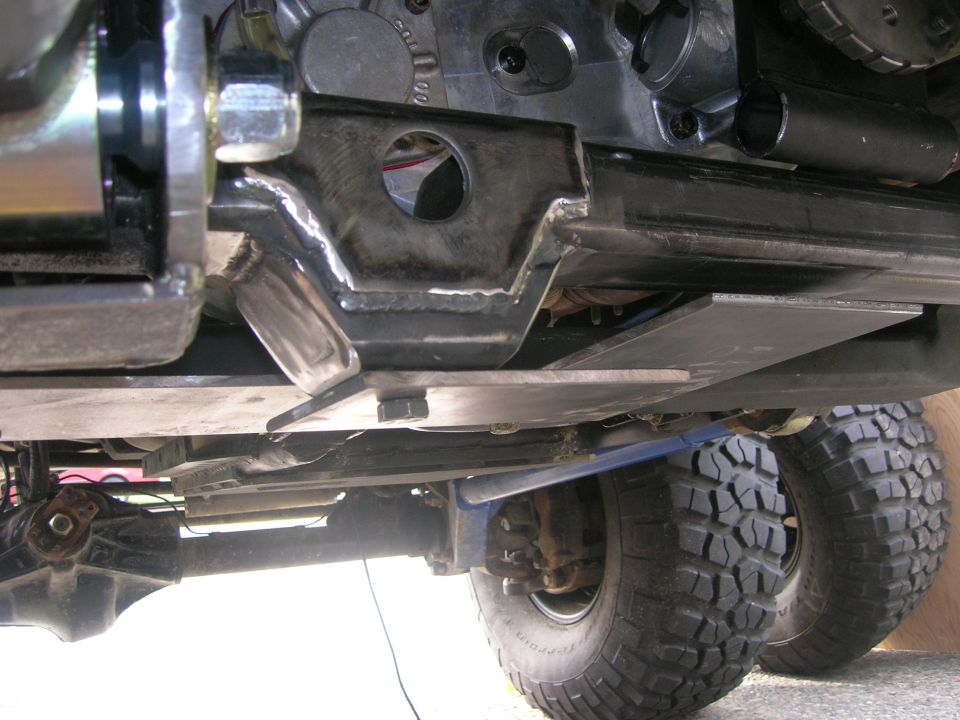Underside of a vehicle with custom skid plate and off-road tires.