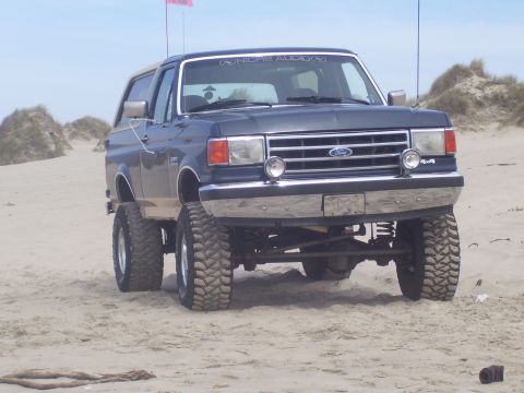 1991 Ford Bronco - A dark blue Ford Bronco is seen from the rear on a dusty road.