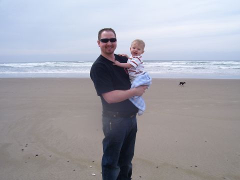 1991 Ford Bronco - A man and a baby enjoy a day at the beach, with a dog in the distance.