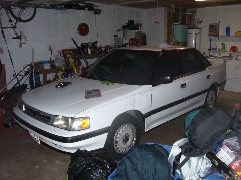 1991 Ford Bronco - This white sedan, likely from the early 1990s, is parked in a cluttered garage. The registry incorrectly identified it as a 1991 Ford Bronc…