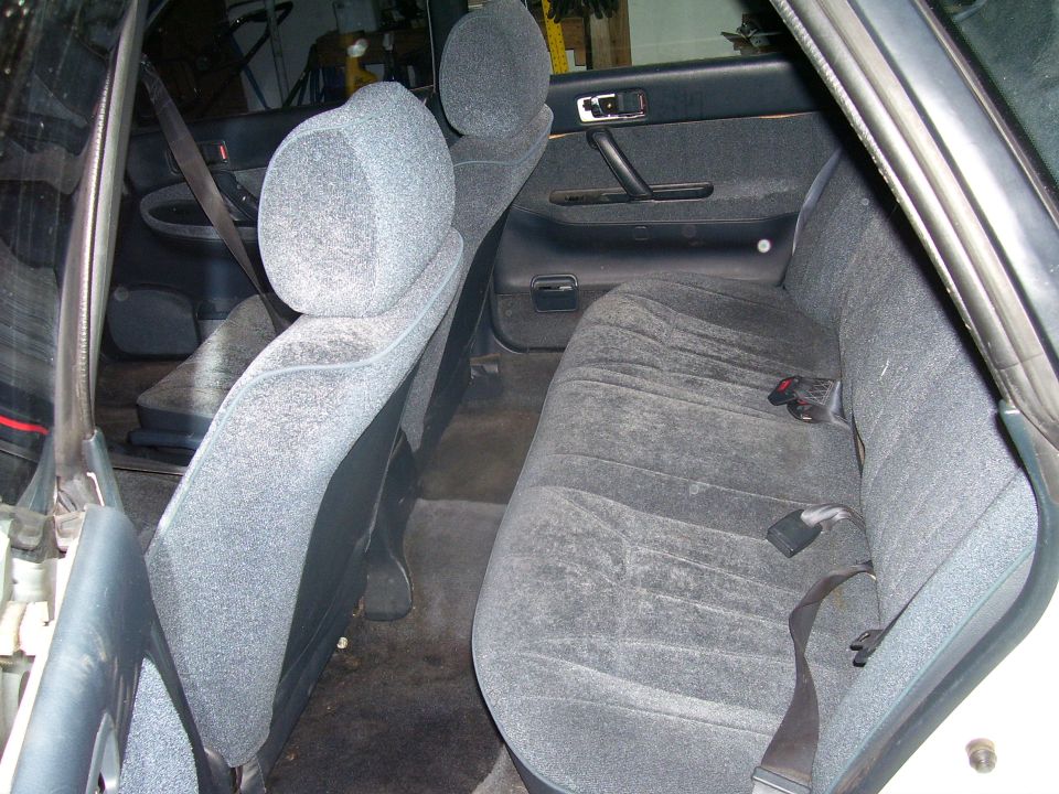 Back seat and door panel of a car interior. Gray fabric seats and dark gray door trim