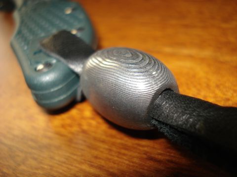 2000 Ford Crown Victoria - A close-up view of a metal bead with a textured surface, attached to a lanyard and a green knife handle.