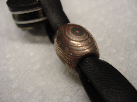 2000 Ford Crown Victoria - An ornamental bead with a metallic, concentric ring design is shown on a black strap.