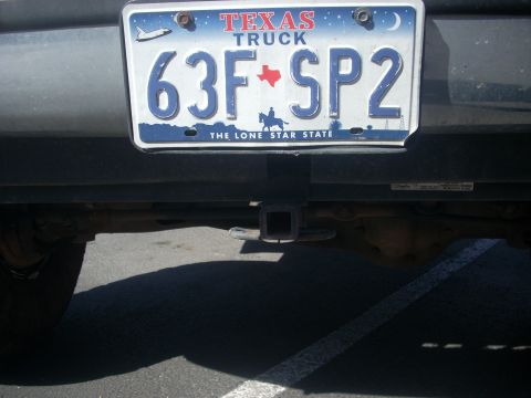1992 Ford Bronco - The rear of a vehicle shows a Texas license plate and a trailer hitch receiver.