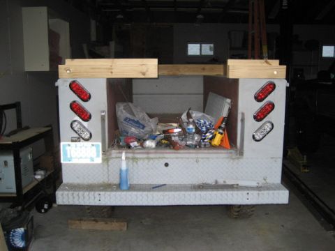 1996 Ford Bronco - The rear of a utility truck bed is shown, filled with various items and equipped with diamond plate bumper and oval trailer lights.