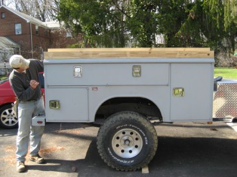 1996 Ford Bronco - Utility truck bed with toolboxes and wooden top, a man is standing next to it.
