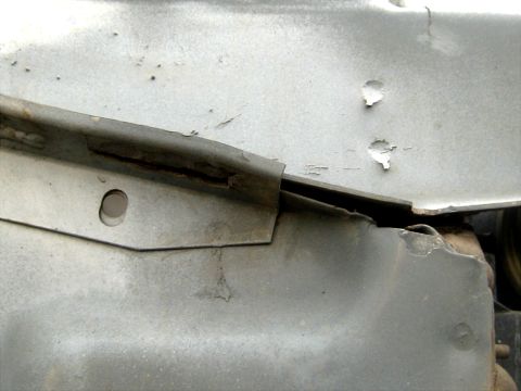 1996 Ford Bronco - Tight shot of a cracked and torn sheet-metal seam on a vehicle's inner structure, where a flanged panel has split away from the body panel…