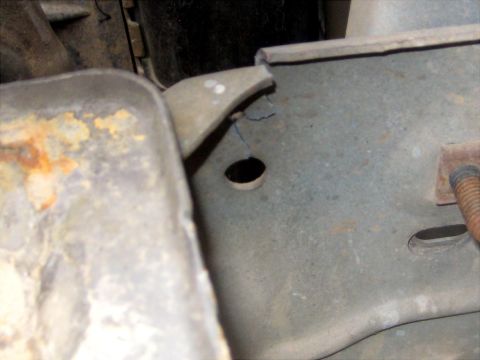 1996 Ford Bronco - Underhood close-up of a bare, weathered frame or inner-fender panel with a fine crack running from the edge down toward a round hole in the…