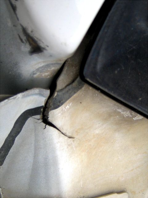 1996 Ford Bronco - Close-up view of damaged plastic trim and a white body panel, showing wear and tear.