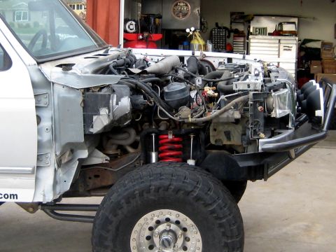 1996 Ford Bronco - White full-size Ford truck with the front clip, fenders and hood removed, showing the V8 engine bay, coil-over shock with red spring, dual…