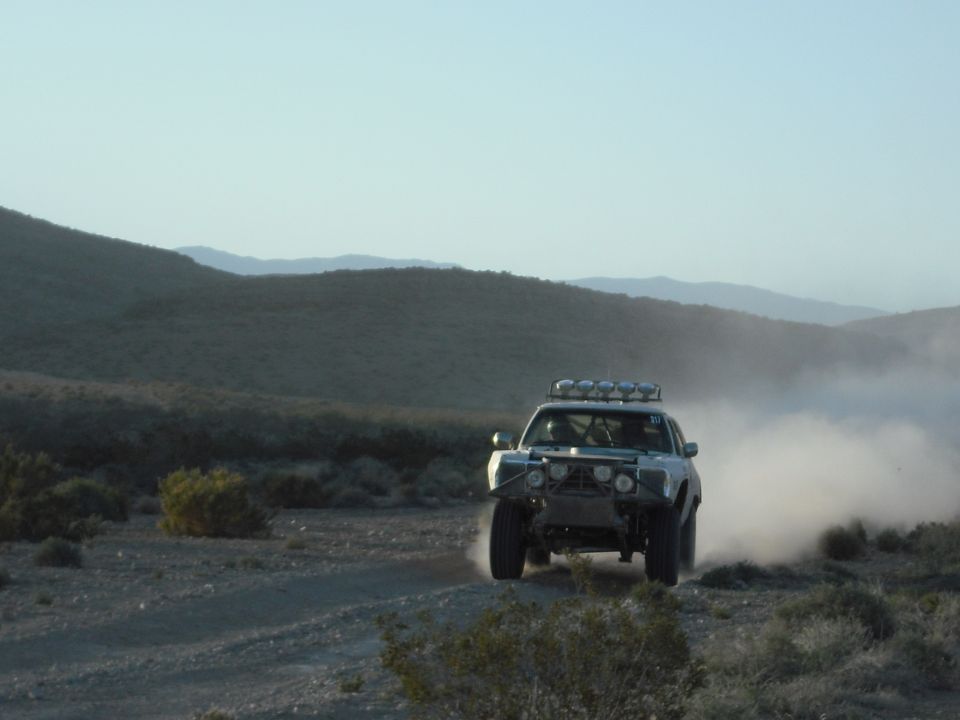 Off-road truck with roof lights kicking up dust on a dirt road