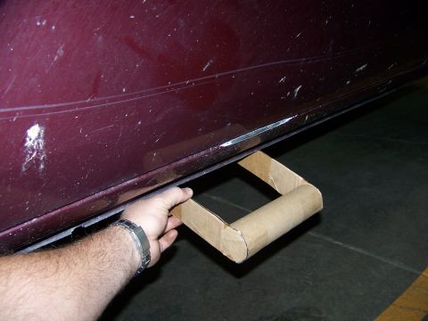2001 Dodge 1500 - A hand holds a temporary cardboard step attached to the lower body of a maroon vehicle.