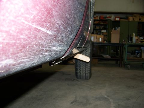 2001 Dodge 1500 - A close-up view of a vehicle's side panel and tire, showing a wooden shim supporting the bodywork.