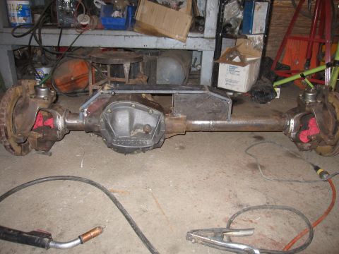 1992 Ford Bronco - A Ford Dana 60 axle assembly is shown in a workshop setting with welding equipment nearby.