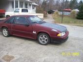 1993 Ford F-150 - A maroon coupe with a black hood sits in a driveway, with another vehicle in the background.