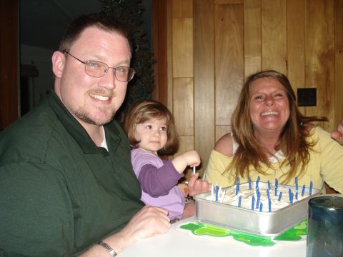 2000 Ford Crown Victoria - A family gathers around a table to celebrate with a cake adorned with numerous candles.