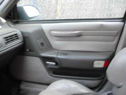 1989 Ford Taurus - Interior door panel of a 1989 Ford Taurus, showing the armrest, speaker grille, and window controls.