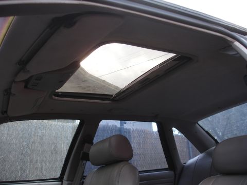 1989 Ford Taurus - The interior of a car is shown with the sunroof open, revealing the sky above.