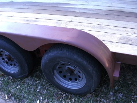 2005 Ford F-250 - Close-up of a trailer's dual wheels and fender, with a wooden deck visible overhead.