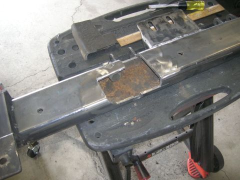1996 Ford Bronco - Close-up of a metal frame part, possibly from a vehicle chassis, on a workbench.
