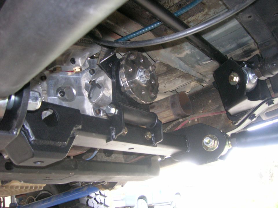 Underside of a vehicle showing aftermarket suspension components and drivetrain parts