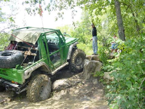 1992 Ford Bronco - This modified SUV is tackling a challenging off-road course with steep inclines and muddy terrain.