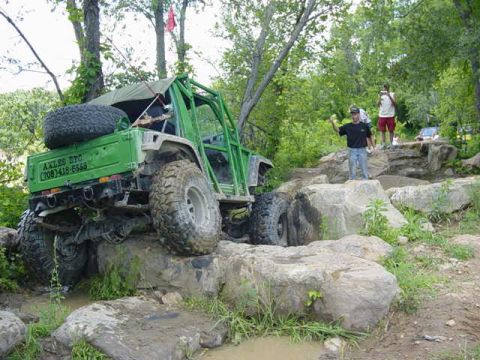 1992 Ford Bronco - An off-road vehicle navigates a rocky terrain, with text visible on its side.