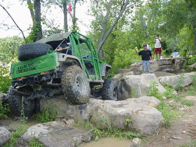 Green off-road vehicle with spare tire on top, text on side reads AXLES ETC (708)418-6555