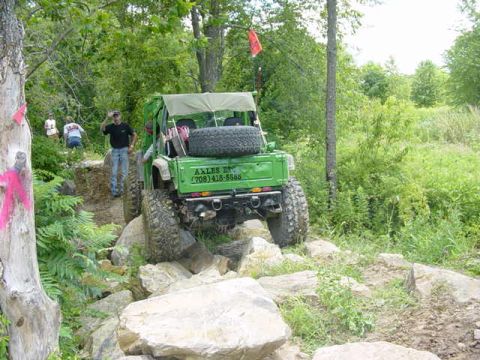 1992 Ford Bronco - A green off-road vehicle tackles a challenging rocky path with a driver and passengers visible.