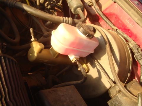 1992 Ford Bronco - Close-up view of the brake booster and master cylinder assembly in a vehicle's engine bay.