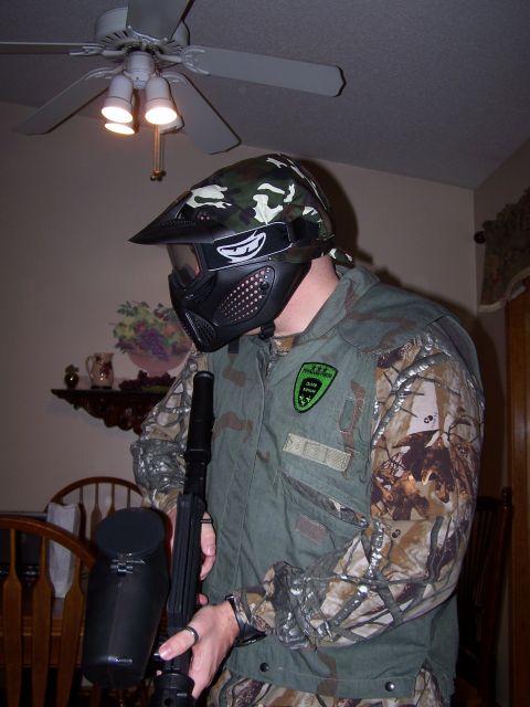 1986 Ford Bronco - Person in camouflage gear and mask holding a paintball marker, ready for a game.