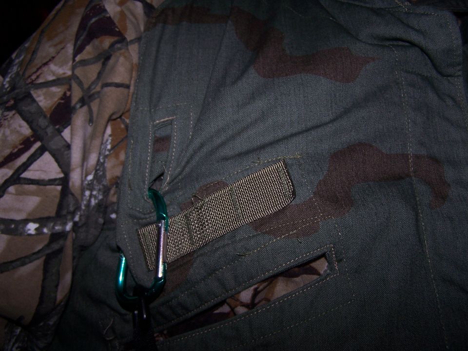 Close-up of camouflage clothing with carabiners attached to a strap