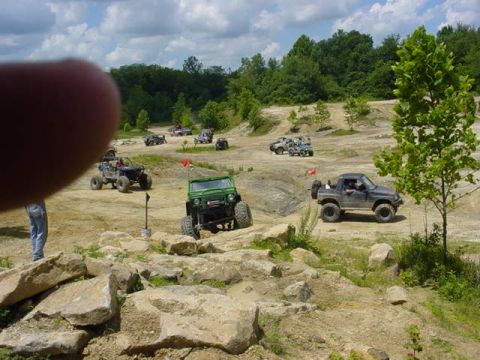 1992 Ford Bronco - Multiple off-road vehicles are seen traversing a challenging dirt and rock course on a sunny day.