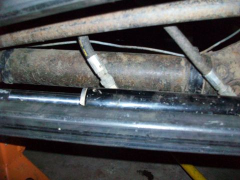 1992 Ford F-350 - Close-up of the undercarriage reveals rusty suspension parts and hydraulic lines, with a black bar in the foreground.