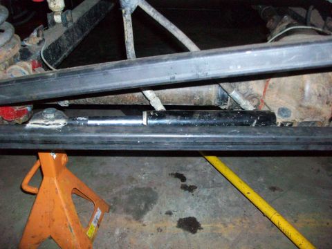 1992 Ford F-350 - A close-up view of a steering stabilizer cylinder, part of the undercarriage of a vehicle.