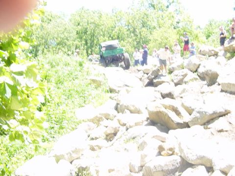1992 Ford Bronco - A green off-road vehicle navigates a challenging rocky course with onlookers present.