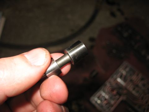 1995 Ford C-350 (Centurion Conversions) - Close-up of a metal component, possibly from a transmission, held by fingers against a blurred background.