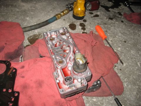 1995 Ford C-350 (Centurion Conversions) - A disassembled transmission valve body sits on red shop towels next to an air hose and screwdrivers.