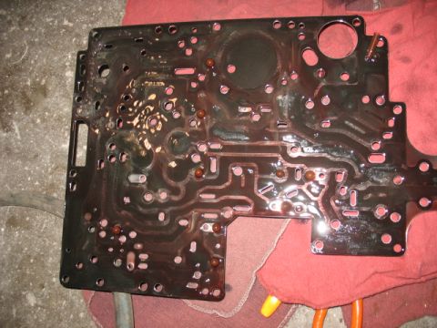 1995 Ford C-350 (Centurion Conversions) - A close-up view of a transmission valve body, showing its intricate internal channels and fluid residue.