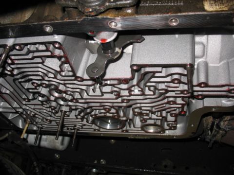 1995 Ford C-350 (Centurion Conversions) - Close-up view of a transmission pan and valve body, showing the intricate fluid channels and a shift lever mechanism.