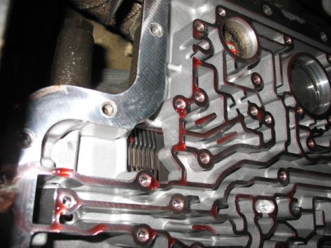 1995 Ford C-350 (Centurion Conversions) - Automatic transmission valve body with red fluid visible in the channels.