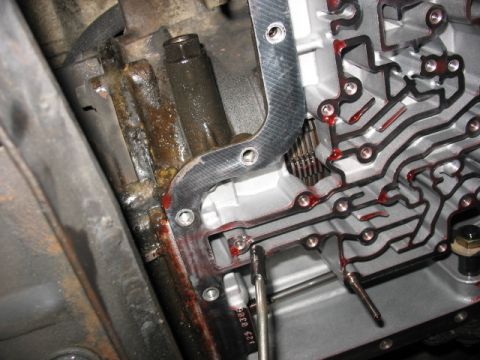 1995 Ford C-350 (Centurion Conversions) - Close-up of a transmission pan gasket with fluid and internal components visible.