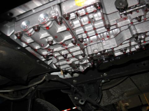 1995 Ford C-350 (Centurion Conversions) - Close-up of a transmission pan showing fluid leaks and a filter, viewed from below.